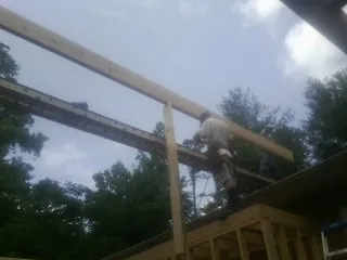 Carpenter setting a ridge beam over a new addition frame — Ice Dam Removal by Roofing Brothers in Bryant