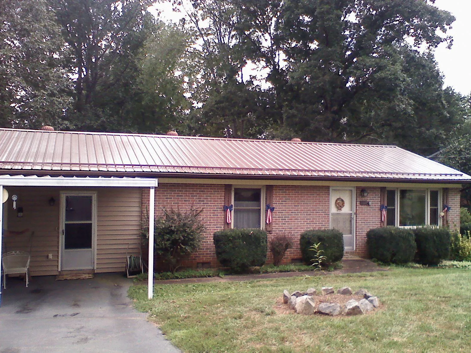 Bronze metal roof and carport on a brick ranch home — Roof Repair work by our crew in Bryant